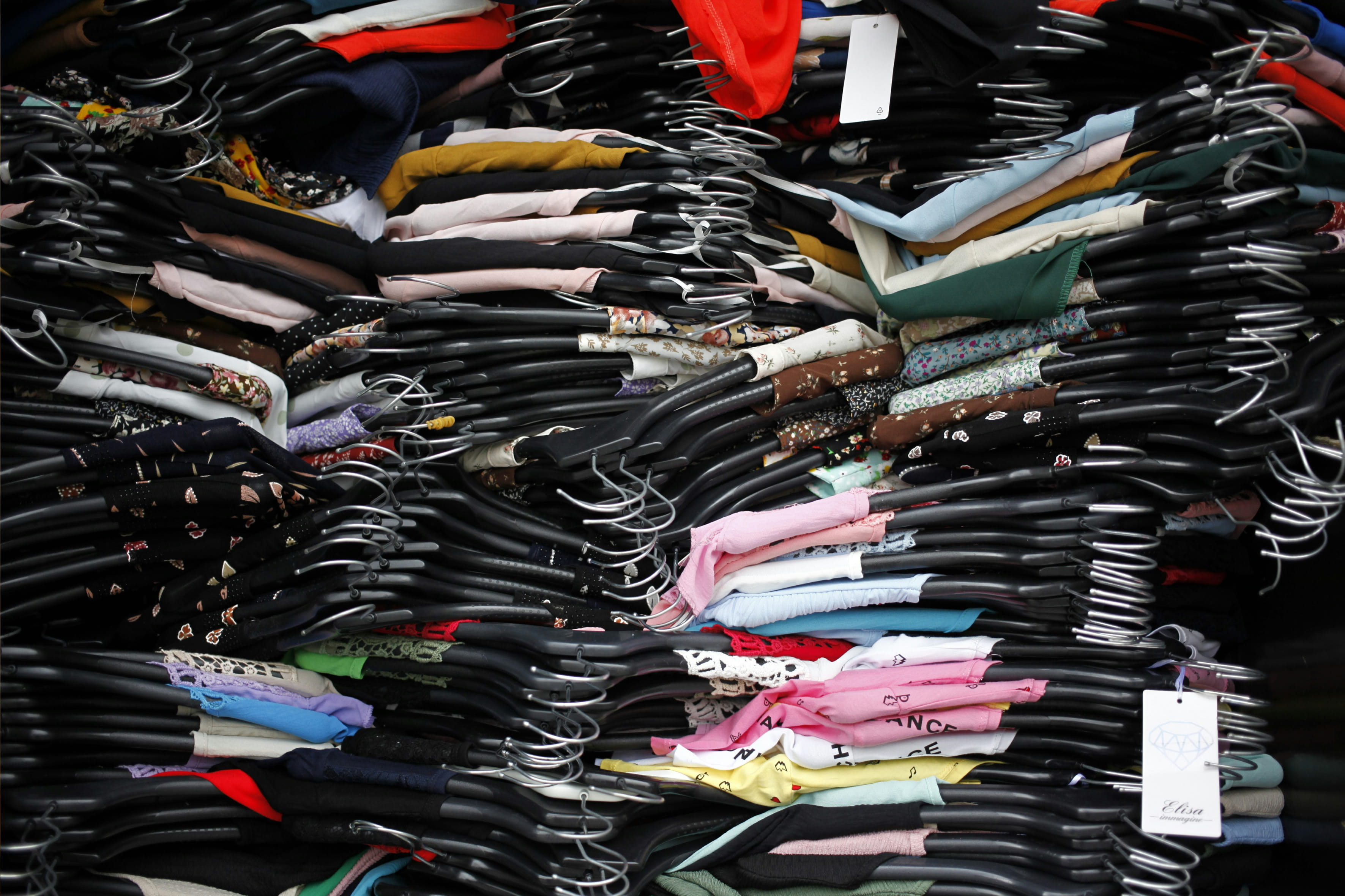 Clothes hanging on racks, densely stacked one above another