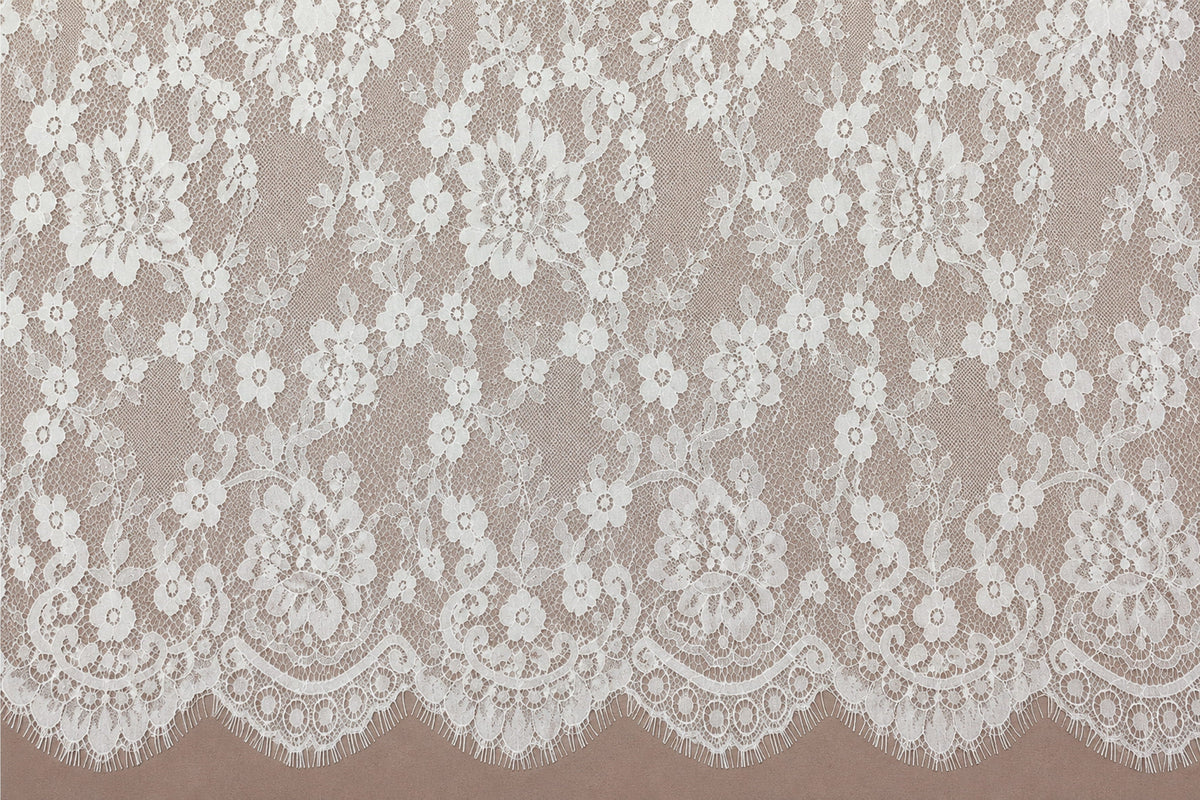 White Chantilly lace with an intricate floral pattern displayed against a soft pink background