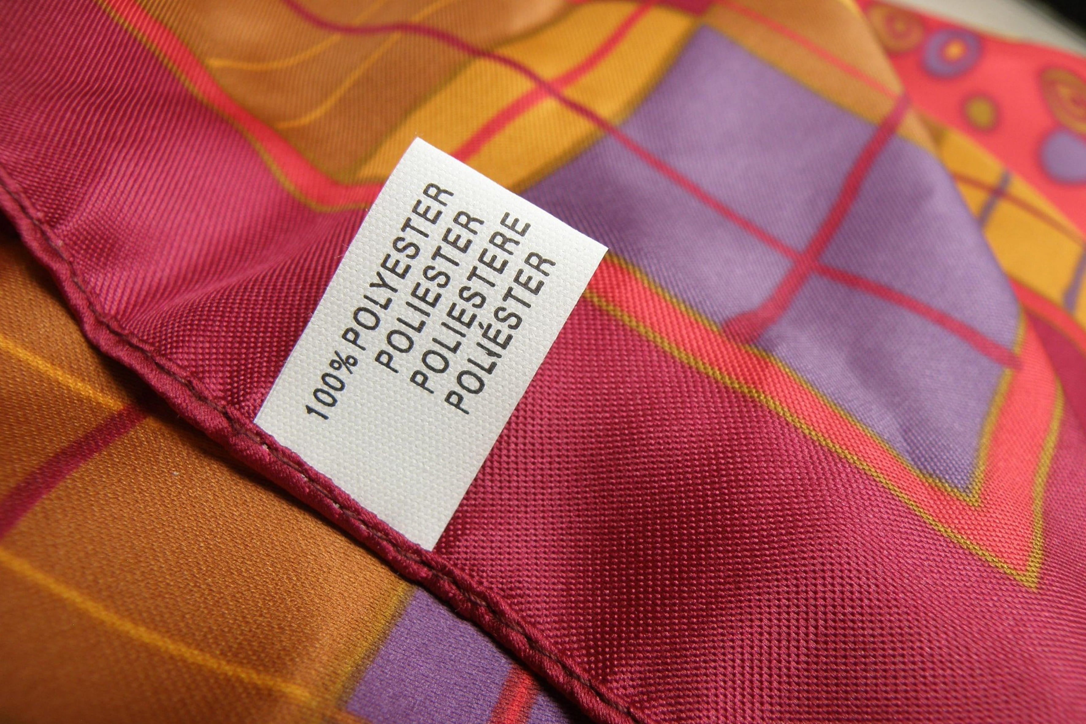 Close-up of a 100% polyester label on a colorful patterned fabric